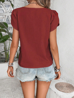 Top monocolore estivo con scollo asimmetrico e maniche a sbuffo perfetto per le vacanze